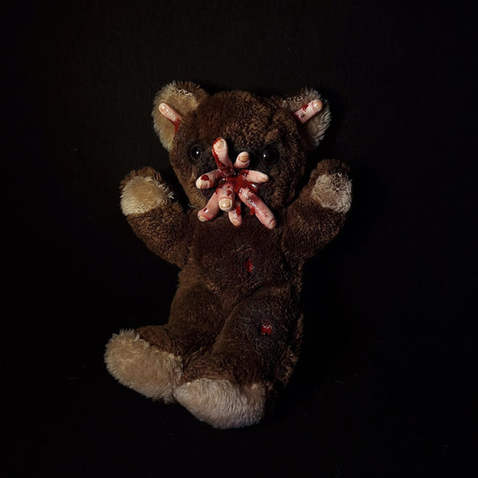 Teddy bear with multiple bloody fingers coming out of his mouth 